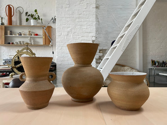 Picture in Des Vases' atelier, in the foreground her unique handcrafted ceramic pieces, the artist stands in the background.